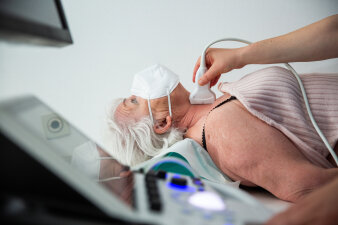 Eine Person wird mit einem Ultraschallgerät auf Brusthöhe untersucht.