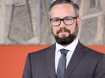 Fotografie eines Mannes im Anzug mit Brille und grau-melierten Haaren und Bart