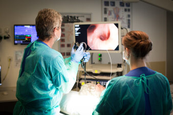 Zwei Personen betrachten mithilfe von Geräten die Bronchien von Innen an einem Bildschirm.