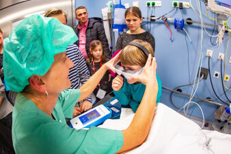 Eine Person zeigt den Anwesenden einen Operationssaal mit Zubehör.