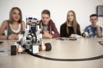 Vier Jugendliche erforschen einen Roboter.