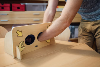 Foto: Lernwerkstatt: Die Montessori Fühlbox © Universität Erfurt eine Hand steckt in einer Holzbox