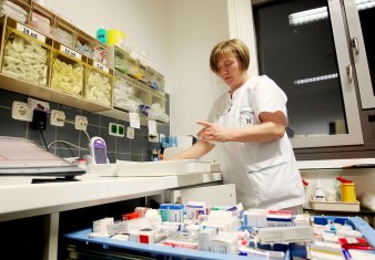 Foto: Medikamentenausgabe © HELIOS Kliniken GmbH Krankenschwester mit einer Vielzahl von Medikamenten in Regalen und auf Tischen
