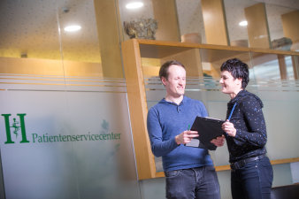 Foto: Patientenservicecenter © Helios Kliniken GmbH weibliche und männliche Person mit Unterlagen in der Hand