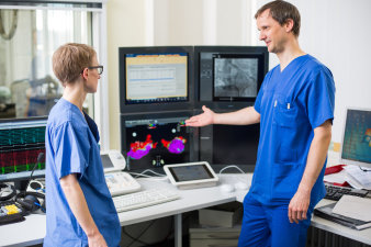 Foto: Echokardiografie © Helios Kliniken GmbH zwei Mediziner stehen am Arbeitsplatz mit Computern und Monitoren