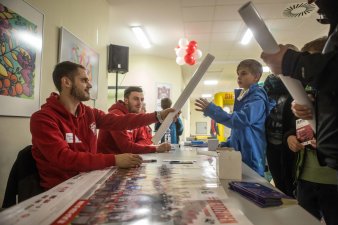 Foto: Torwandschießen mit FC RWE © Helios Kliniken GmbH Ein Spieler übergibt einem Kind ein signiertes Plakat