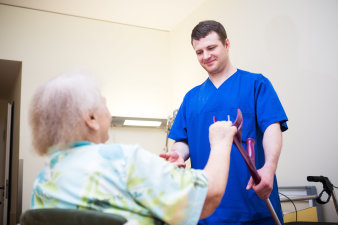 Foto: Geriatrie © Helios Kliniken GmbH Pfleger hilft älteren Frau Aufstehen