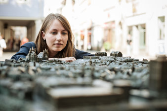 Foto: Wohnentscheidung © Jens Hauspurg Eine junge Frau betrachtet das Miniatur-Stadtmodell von Erfurt.