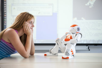 Foto: Der Naoroboter © Jens Hauspurg Eine junge Frau betrachet einen humanoiden Roboter (Nao).