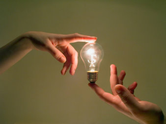 Foto: Das Messen mit Licht © yogo / Fotolia Zwei Hände halten jeweils mit dem Zeigefinger eine Glühbirne fest.