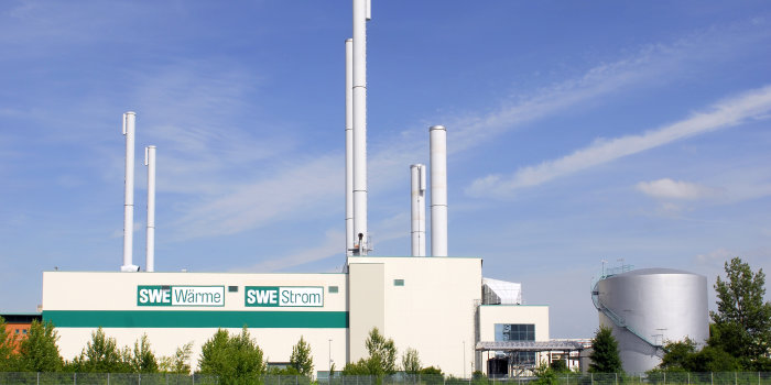 Weißes Gebäude der Stadtwerke Erfurt mit den Aufschriften "SWE Wärme" und "SWE Strom" vor einem strahlend blauen Himmel mit Wolken.