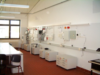Foto: Blick in einen Raum mit Gebäudeleitsystemen © Jörg Gengelbach Raum mit weißer Wand und weißen Geräten zur Gebäudeleitung