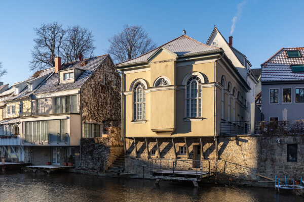 Gelbes Gebäude der Kleinen Synagoge Erfurt an der Gera liegend im Licht- und Schattenspiel