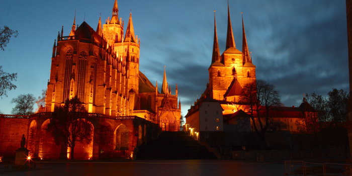 Dom St. Marien und Severi-Kirche hell erleuchtet vor Nachthimmel.