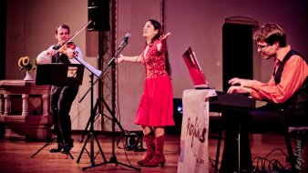 Foto: Rozhinkes © Hornemann Eine Sängerin und 2 mit Instrumenten spielende Musiker