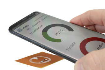 Smartphone wird über NFC-Sensor-Tag gehalten. Das Display zeigt die Messwerte.