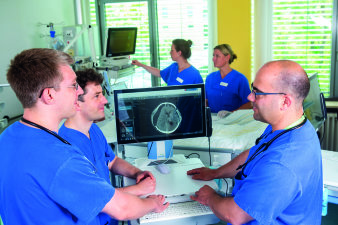 Foto: Moderne Intensivmedizin © Helios Kliniken GmbH fünf Personen an zwei Geräten mit Monitoren