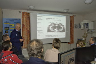 Foto: Vortrag von Prof. Hans Pistner © Dr. Frank Schaefer Männliche Person steht neben einer Leinwandpräsenation und Zuhörern im Raum