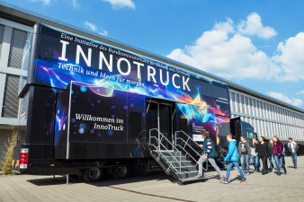 Foto: InnoTruck © BMBF-Initiative InnoTruck / FLAD & FLAD Communication GmbH ein doppelstöckiges, schwarzes Ausstellungsfahrzeug