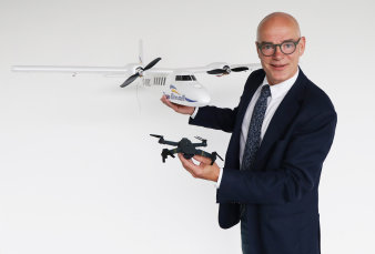 Foto: Der Rektor der Fachhochschule mit Drohnen © Kristin Thieme Mann im Anzug mit zwei Drohnen verschiedener Art und Größe in den Händen
