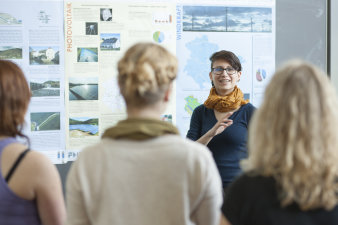 Foto: Studierende präsentieren ihre Abschlussarbeiten © Jens Hauspurg Studierende vor Tafeln mit Abbildungen