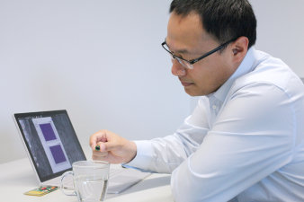 Foto: Tee auf Sendung – mit batterielosem RFID-Sensor-Transponder © IMMS / Beate Hövelmans Ein Forscher des IMMS wirft einen Cent-Stück-großen batterielosen RFID-Transponder in eine Tasse mit heißem Wasser.